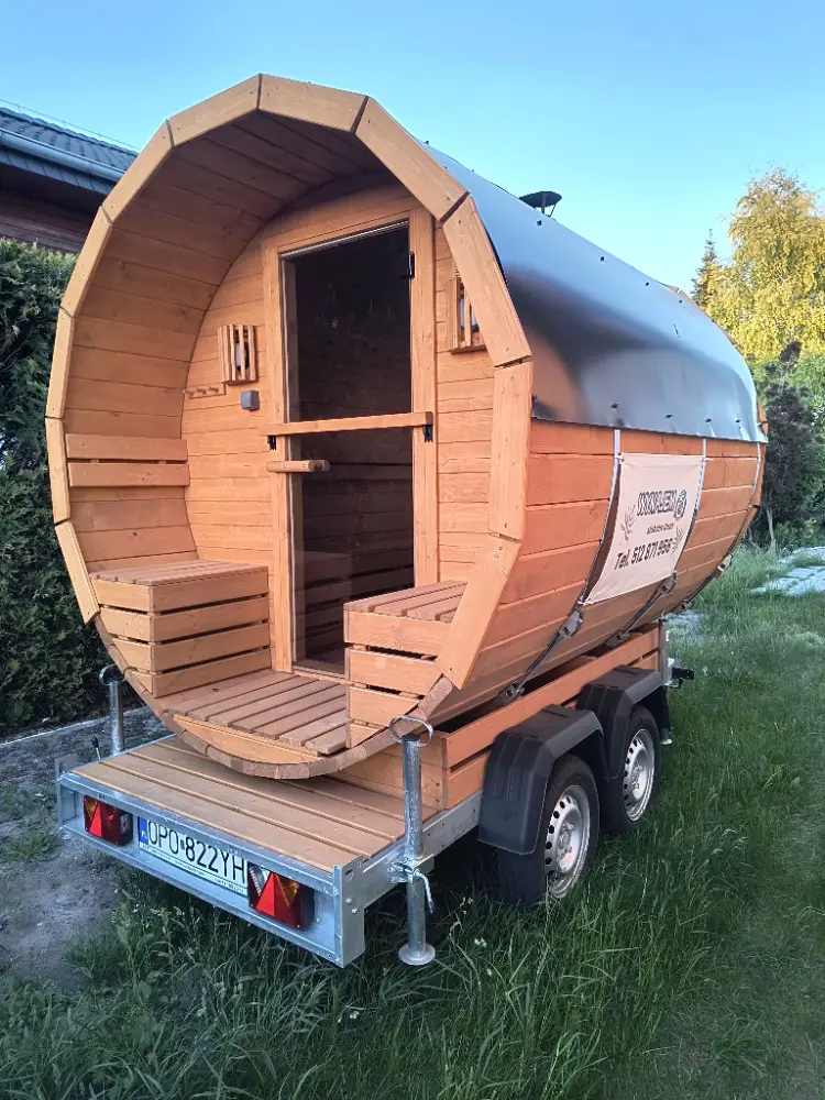 Mobilna sauna fińska na przyczepie z otwartymi drzwiami w ogrodzie