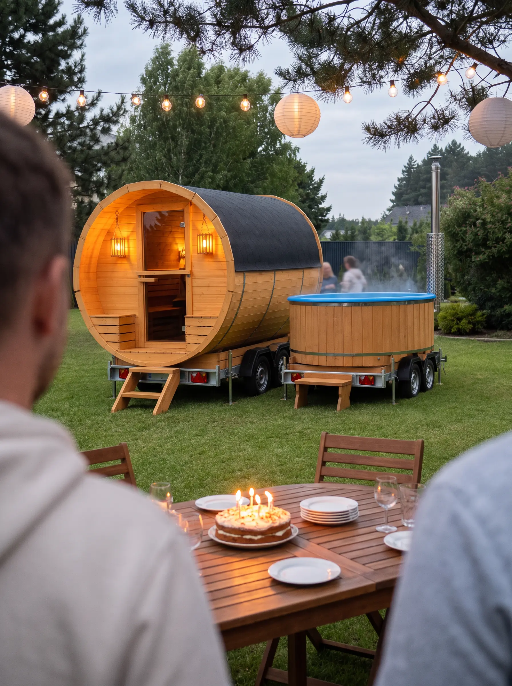 Stół z tortem w ogrodzie, w tle mobilna sauna i balia ogrodowa na przyczepach